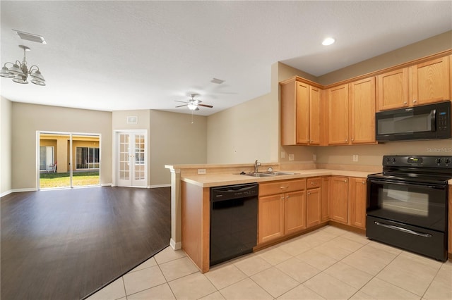 kitchen featuring visible vents, open floor plan, a sink, a peninsula, and black appliances