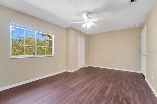 empty room with dark wood-style floors, ceiling fan, baseboards, and a textured ceiling