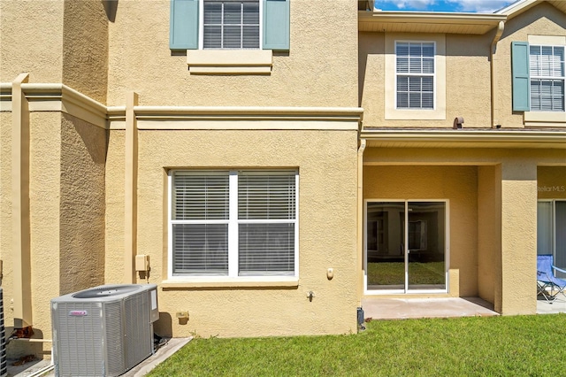 rear view of house featuring central AC unit and stucco siding