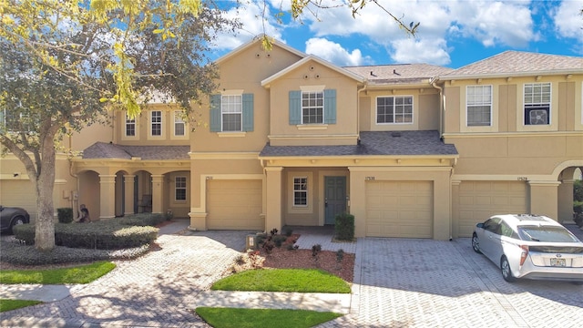 view of front of house featuring a garage, driveway, a shingled roof, and stucco siding