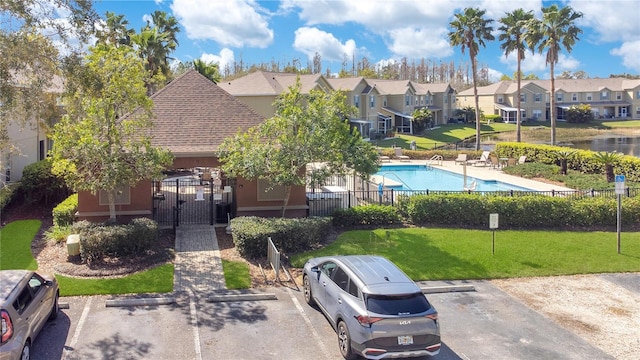 view of front of property with fence, a gate, a residential view, uncovered parking, and a front yard