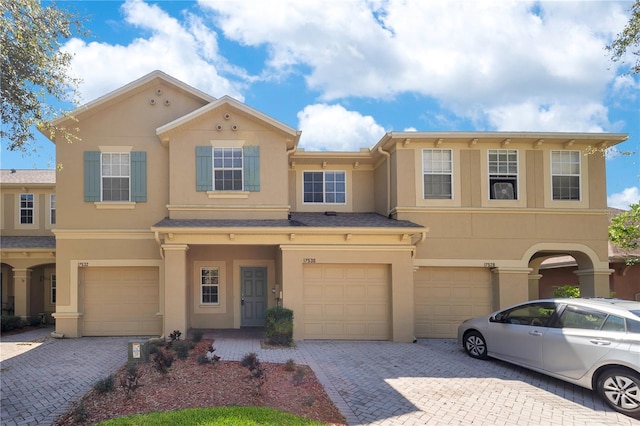 view of front of property featuring decorative driveway, an attached garage, and stucco siding