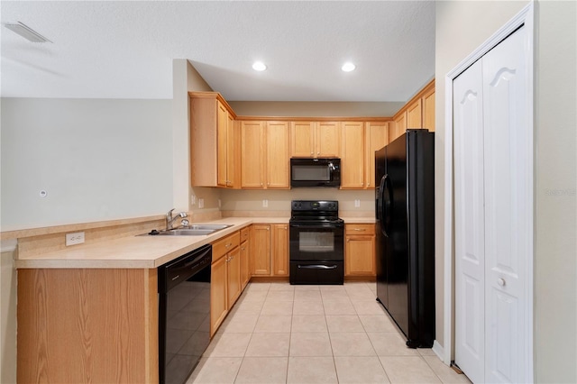 kitchen featuring light tile patterned floors, light countertops, black appliances, light brown cabinets, and a sink