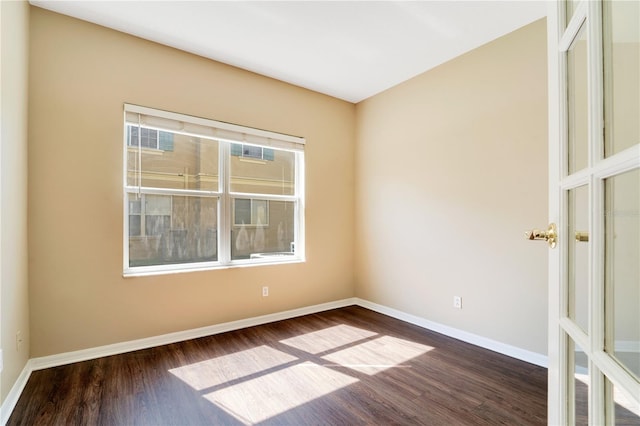 unfurnished room with dark wood-type flooring and baseboards