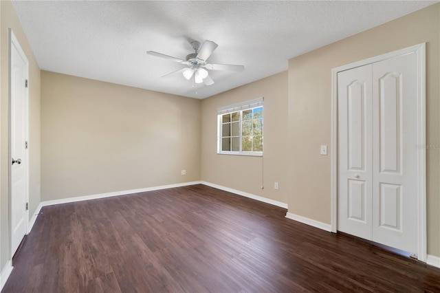 unfurnished bedroom with dark wood finished floors, a textured ceiling, baseboards, and ceiling fan