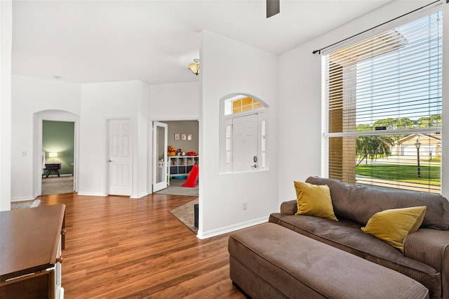 entryway featuring arched walkways, ceiling fan, wood finished floors, and baseboards