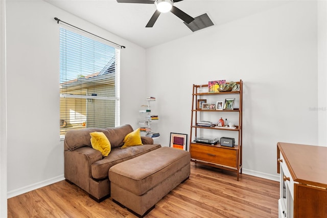 living area featuring a ceiling fan, light wood-style flooring, and baseboards