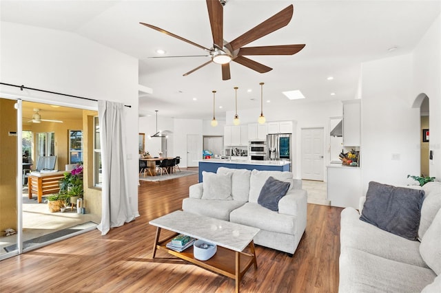 living area featuring arched walkways, recessed lighting, light wood-style flooring, a ceiling fan, and vaulted ceiling