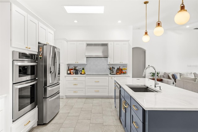 kitchen with stainless steel appliances, white cabinetry, ventilation hood, and a sink