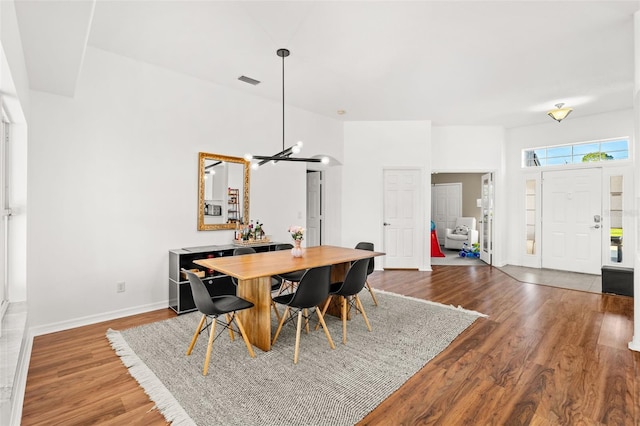 dining space with visible vents, a notable chandelier, baseboards, and wood finished floors