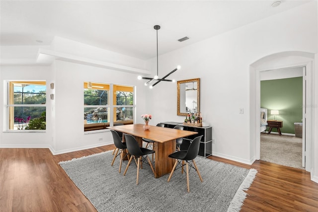 dining space with arched walkways, baseboards, wood finished floors, and a healthy amount of sunlight