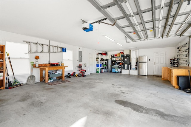 garage with electric panel, a garage door opener, a workshop area, and freestanding refrigerator