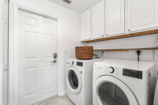 washroom featuring cabinet space, washing machine and dryer, visible vents, and light tile patterned flooring