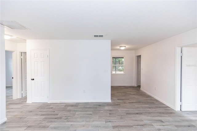 spare room with light wood finished floors, visible vents, and baseboards