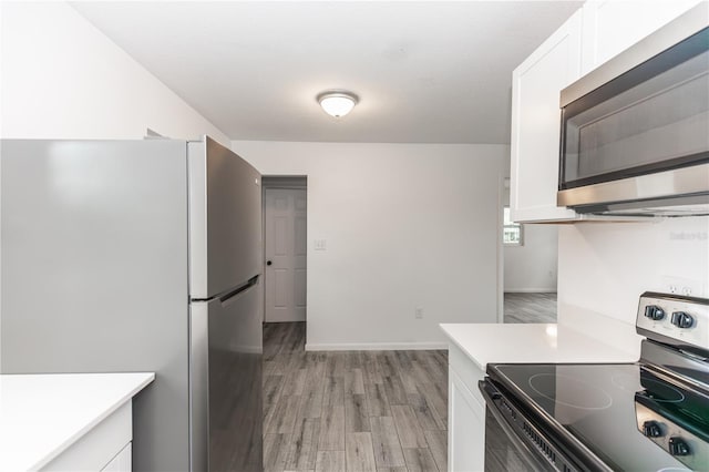 kitchen featuring appliances with stainless steel finishes, white cabinets, light countertops, and light wood finished floors