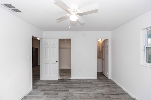 unfurnished bedroom featuring light wood finished floors, visible vents, a spacious closet, ensuite bath, and baseboards