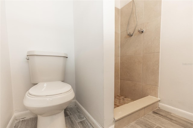 full bathroom with toilet, a shower stall, wood tiled floor, and baseboards