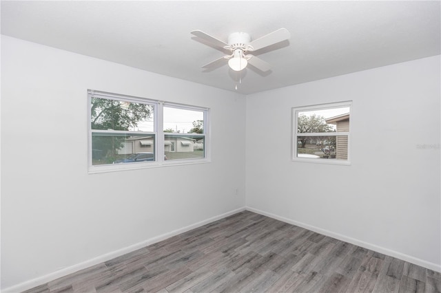 empty room with wood finished floors, a ceiling fan, and baseboards