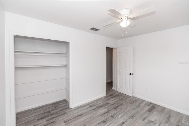 unfurnished bedroom featuring light wood-type flooring, baseboards, visible vents, and a closet