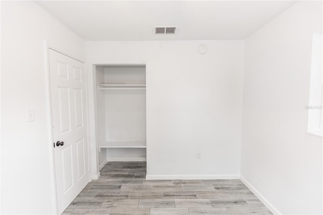 unfurnished bedroom featuring light wood finished floors, baseboards, visible vents, and a closet