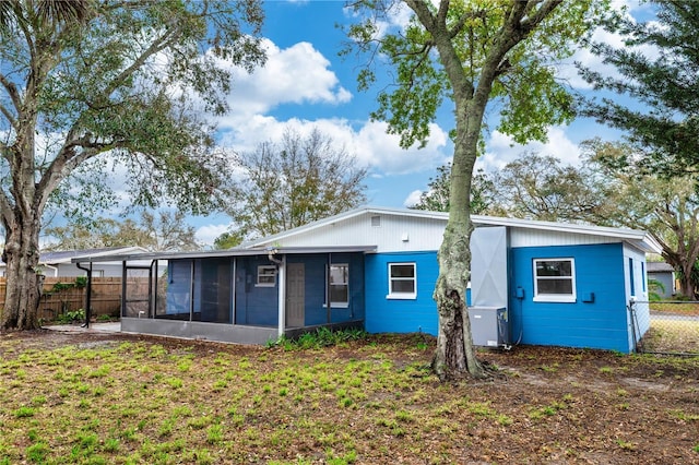 rear view of house with fence and a sunroom