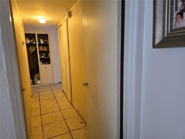 hall featuring light tile patterned floors and a textured ceiling