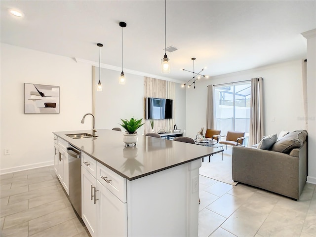 kitchen featuring pendant lighting, a center island with sink, open floor plan, white cabinets, and a sink