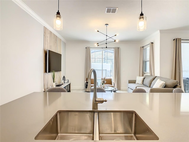 kitchen featuring pendant lighting, visible vents, ornamental molding, open floor plan, and a sink