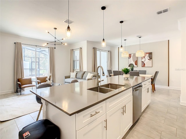 kitchen with open floor plan, hanging light fixtures, a kitchen island with sink, white cabinetry, and a sink