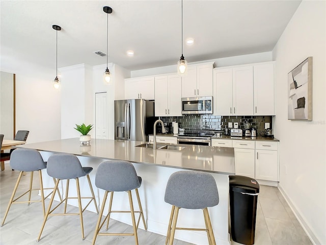 kitchen featuring appliances with stainless steel finishes, white cabinetry, a center island with sink, and a sink