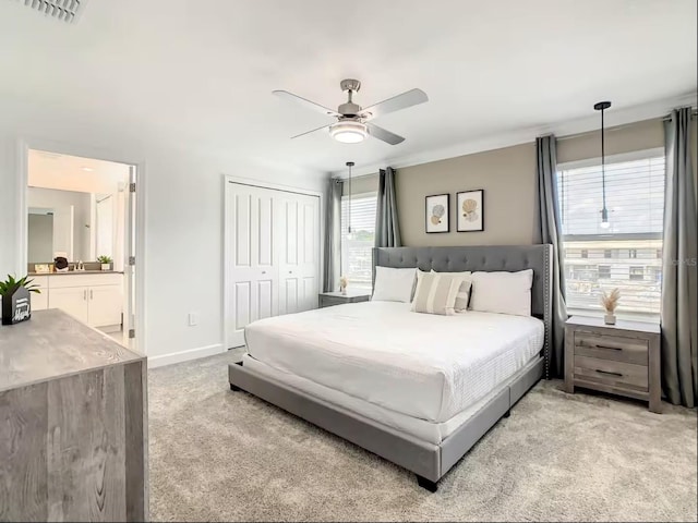 bedroom featuring connected bathroom, light carpet, visible vents, baseboards, and a closet