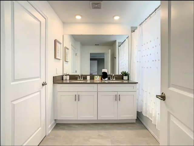 bathroom featuring double vanity, shower / bath combination with curtain, visible vents, and a sink