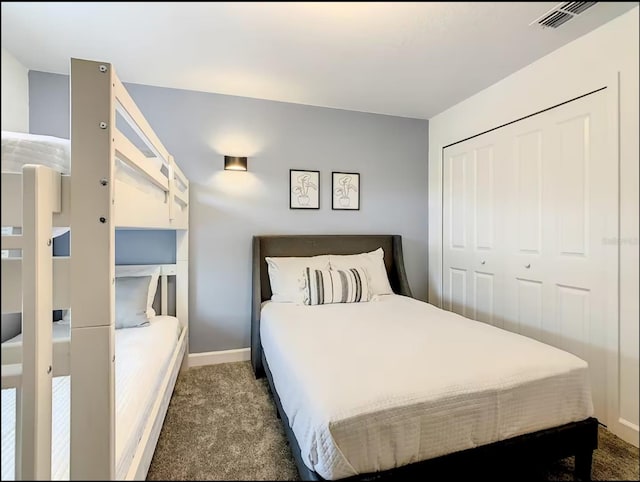 bedroom featuring a closet, visible vents, dark carpet, and baseboards