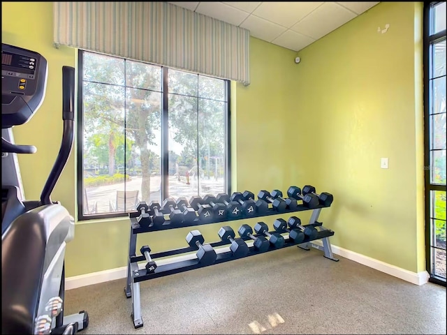 exercise room with baseboards and a drop ceiling