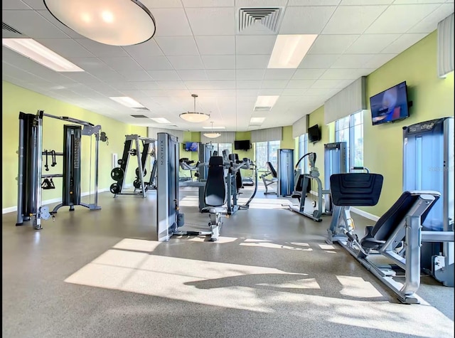 exercise room with visible vents, a drop ceiling, and baseboards