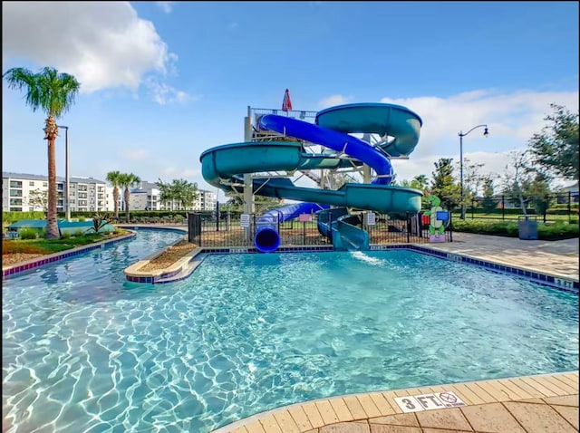 view of pool with a water slide and fence