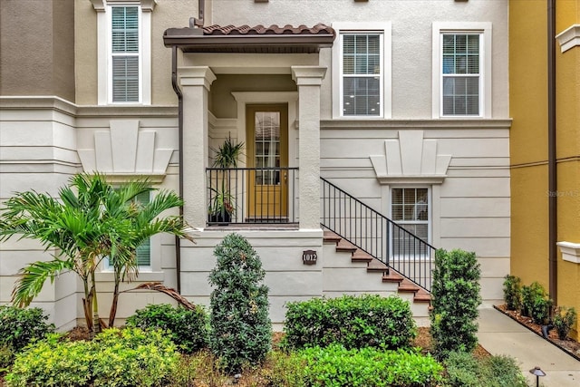 property entrance featuring a tile roof and stucco siding