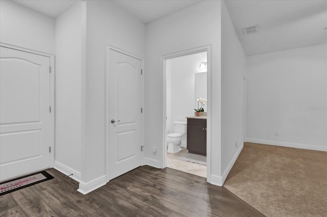 foyer with baseboards, visible vents, and dark wood-style flooring