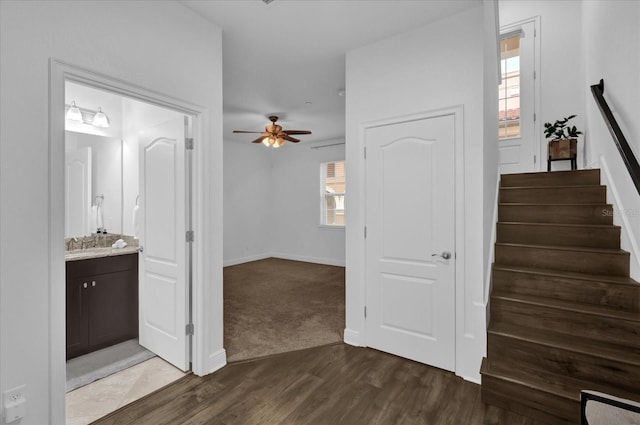 interior space featuring dark wood-style floors, baseboards, stairway, and a ceiling fan