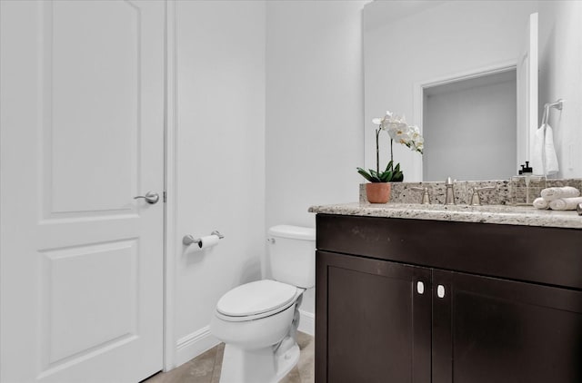 half bath featuring vanity, toilet, and baseboards