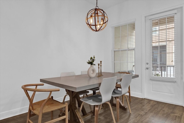 dining room featuring a notable chandelier, dark wood-type flooring, and baseboards