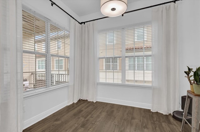 unfurnished room featuring dark wood-style floors, plenty of natural light, and baseboards