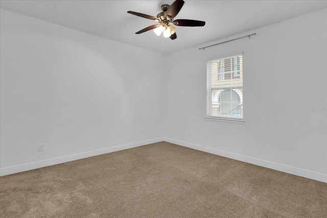 carpeted empty room featuring ceiling fan and baseboards