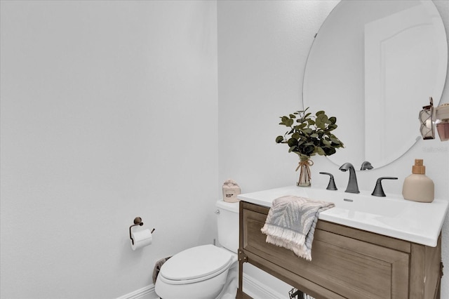 bathroom featuring toilet, vanity, and baseboards