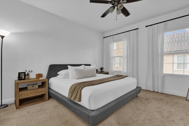 carpeted bedroom with a ceiling fan, multiple windows, and baseboards