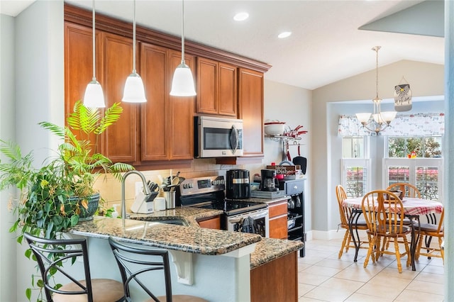 kitchen featuring stone counters, a sink, hanging light fixtures, appliances with stainless steel finishes, and brown cabinetry