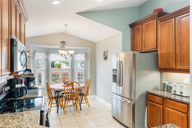 kitchen with stainless steel appliances, lofted ceiling, brown cabinets, and light stone countertops