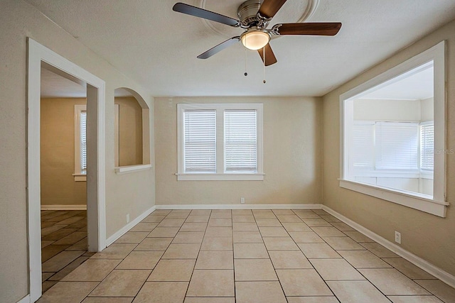 spare room featuring light tile patterned floors, baseboards, and ceiling fan