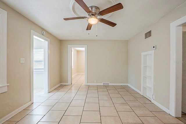 spare room featuring light tile patterned floors, visible vents, and baseboards