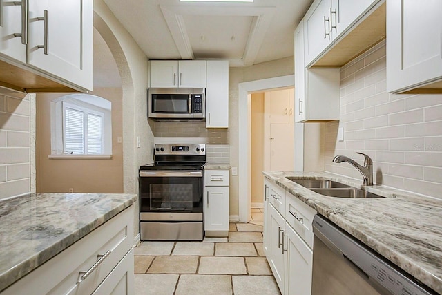 kitchen featuring decorative backsplash, white cabinets, appliances with stainless steel finishes, and a sink